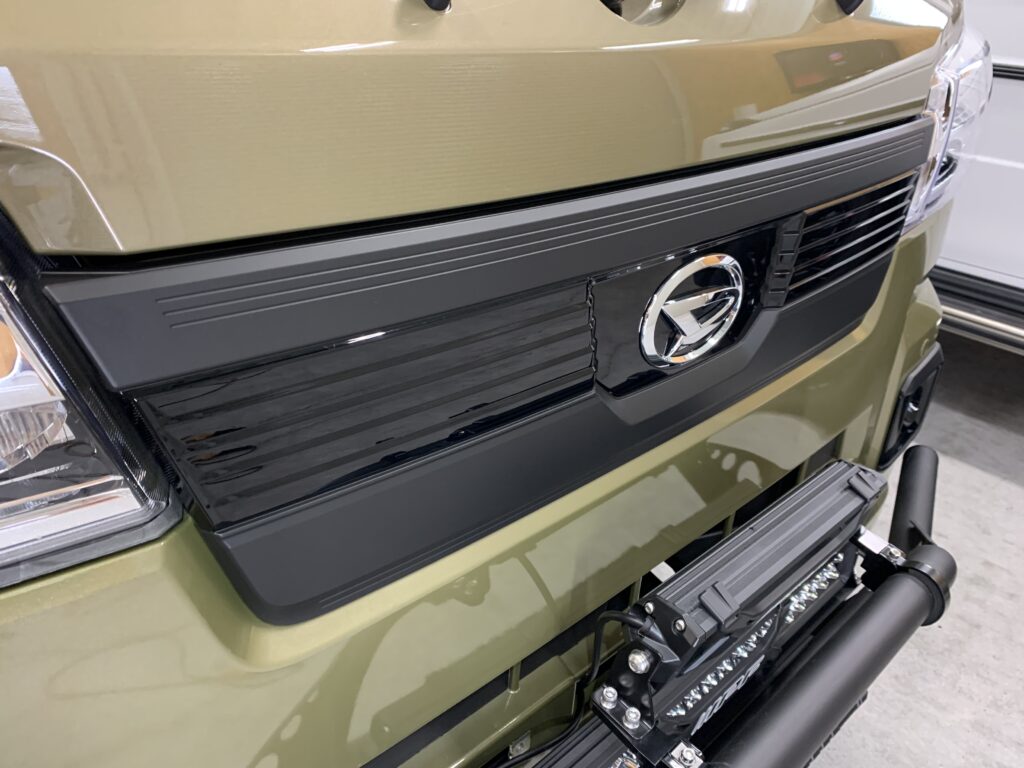 カーラッピング施工後のフロントグリル完成状態。ブラックアウトされたグリルがオリーブグリーンのボディカラーを引き締め、無骨で精悍なフロントフェイスに仕上がった事例。