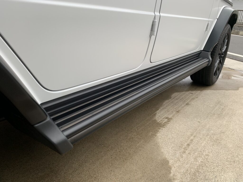 メルセデス・ベンツ G400dのサイドステップにプロテクションフィルムを施工した状態。白いボディとブラックのステップ部分のコントラストがわかる施工後写真。