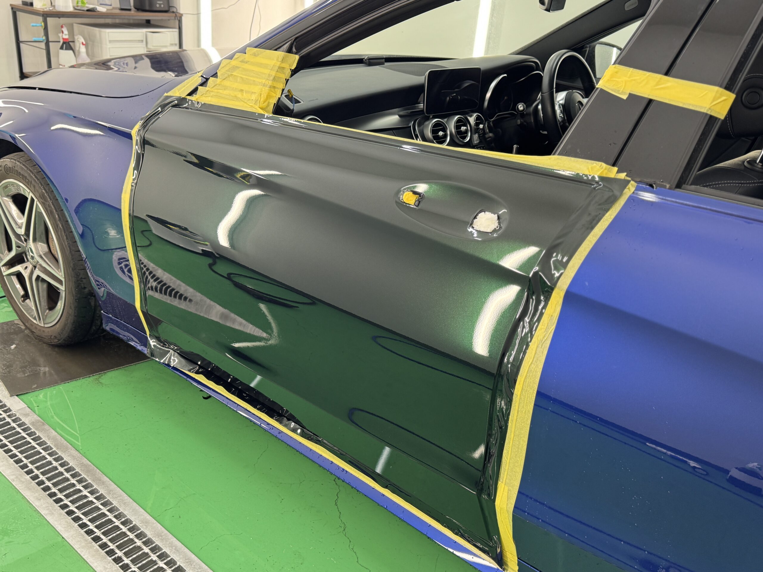 ドアパネルへカラープロテクションフィルムを施工中。位置合わせを行いながら丁寧に貼り込みを進める様子