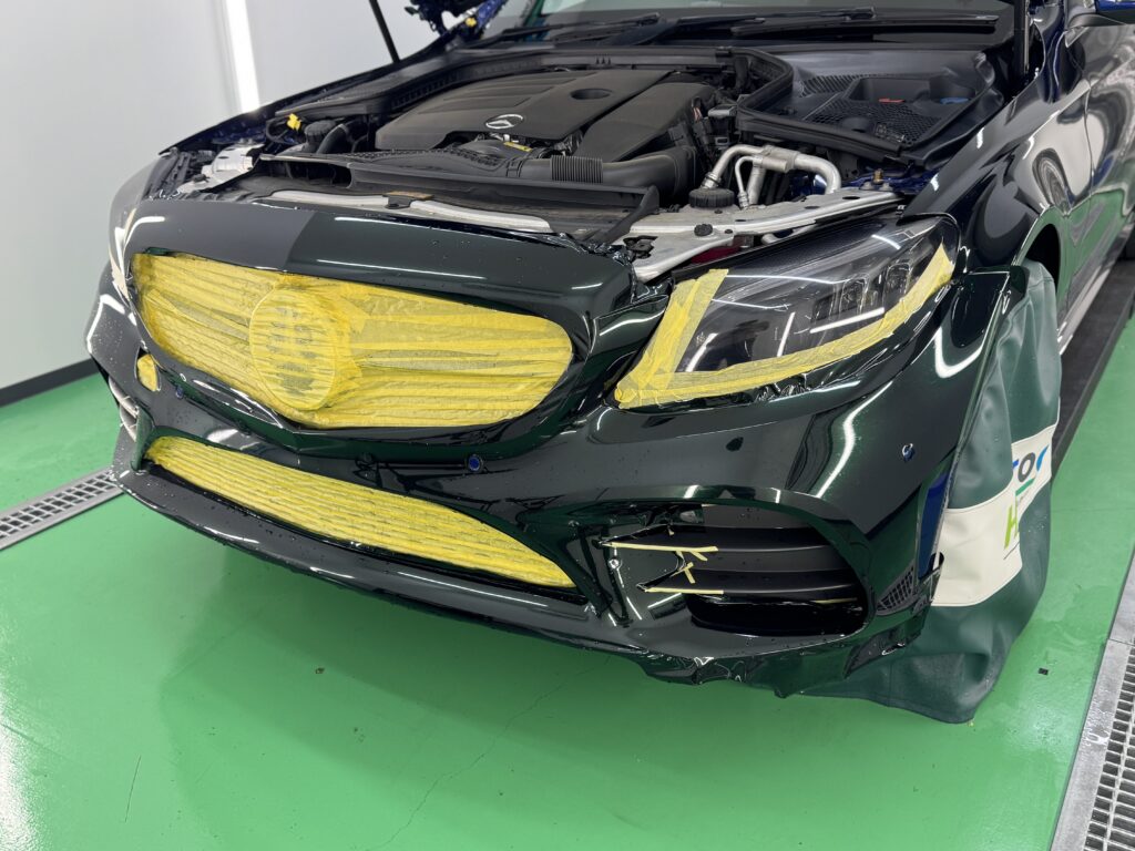 フロントバンパーへカラープロテクションフィルムを施工中。複雑な形状に合わせて貼り込みを行う作業風景