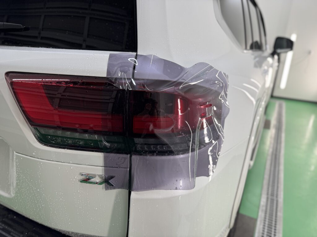 ランクル300のテールランプにスモークプロテクションフィルムを施工している様子。