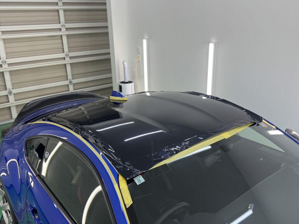 SUBARU BRZのルーフラッピング施工中の写真。ブラック系フィルムをルーフ全体に仮合わせし、施工を行っている様子。