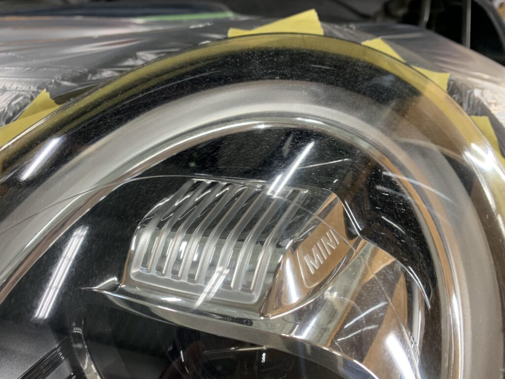 MINI JCWのヘッドライト表面に発生した細かなクラックや劣化状態を確認している様子
