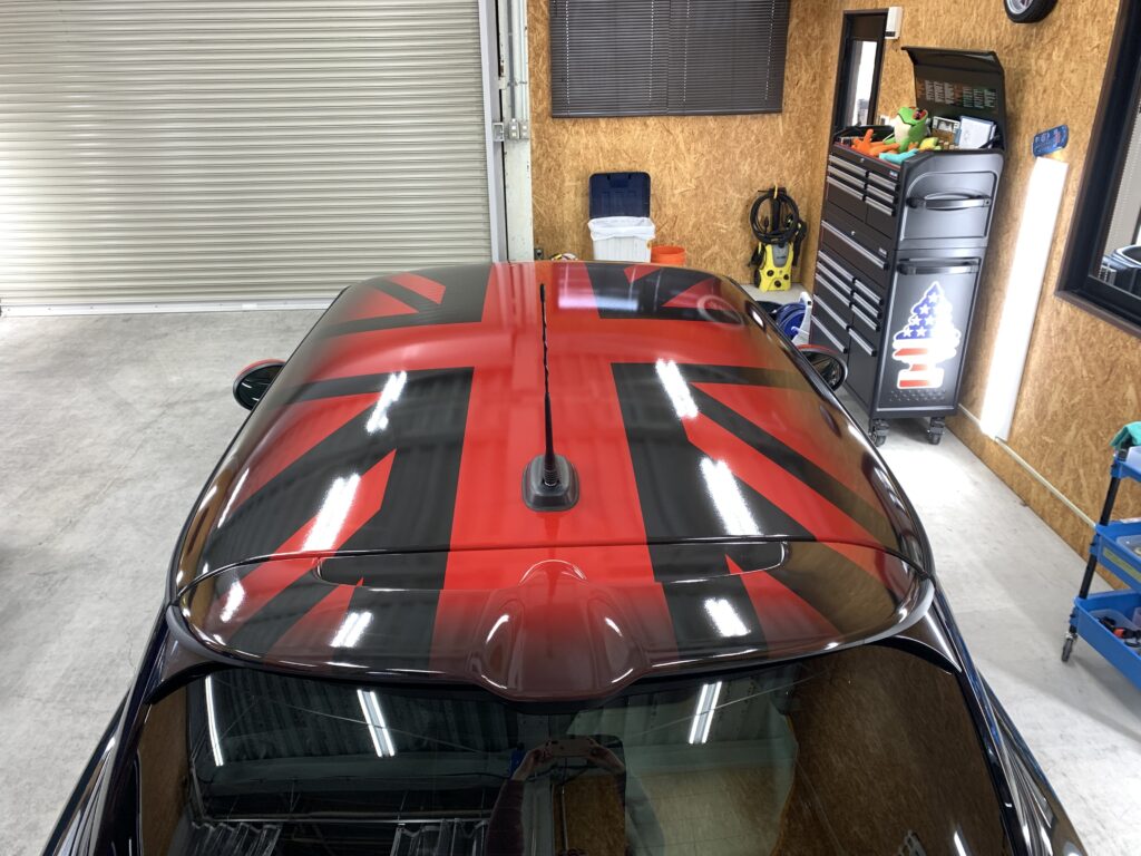 真上から撮影したMINI F56 JCWのルーフラッピング完成写真。左右対称にデザインされたブラックとレッドのユニオンジャック柄が、MINI特有のルーフデザインをより印象的に演出している。