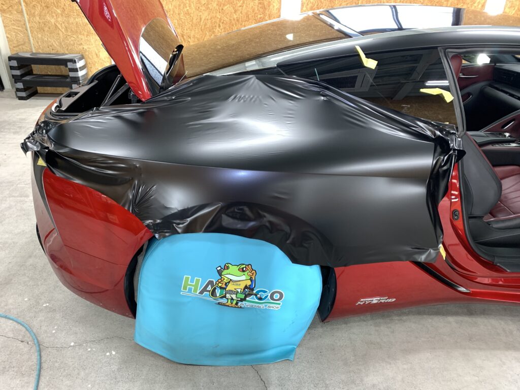 レクサスLC500hのリアフェンダー施工中の様子。大判フィルムを使用し、美しいラインに合わせてラッピングしている工程写真。