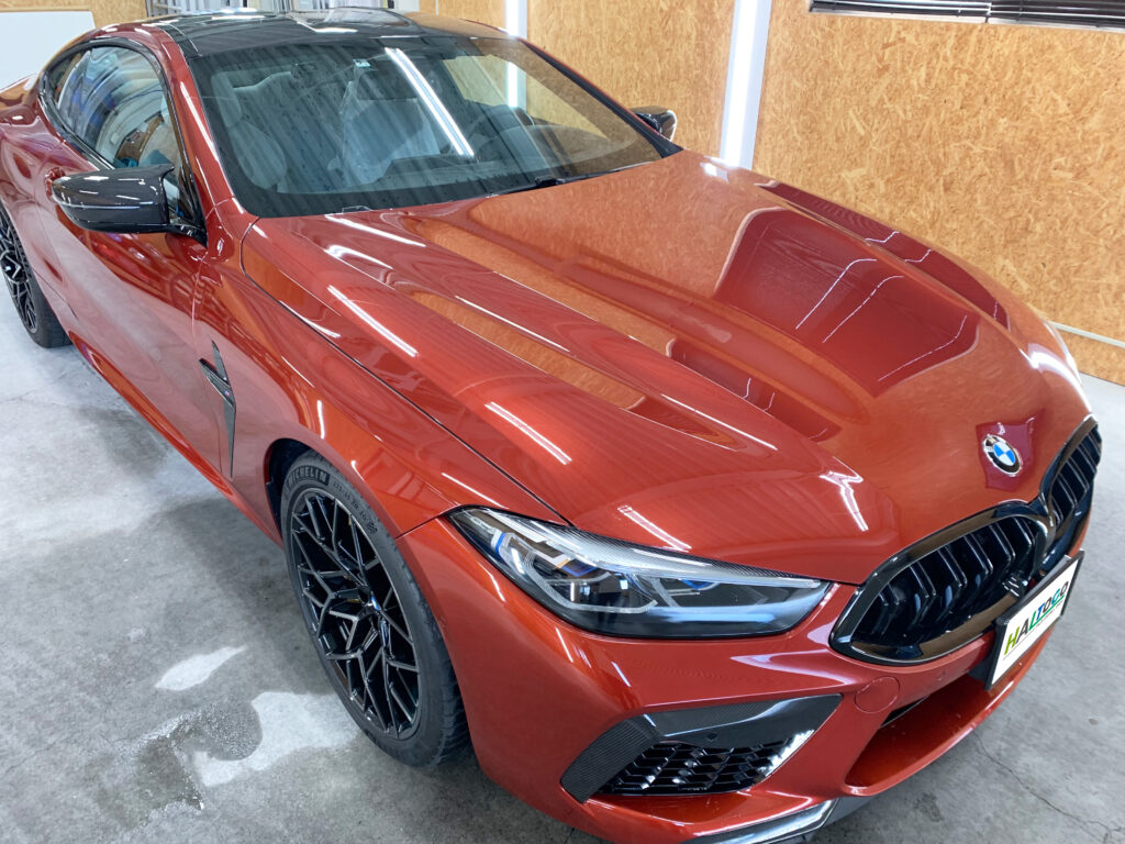 BMW M8のボンネットプロテクション施工後の完成写真。透明プロテクションフィルムにより飛び石や傷から塗装を守りつつ、美しいボディラインと光沢感を維持している。