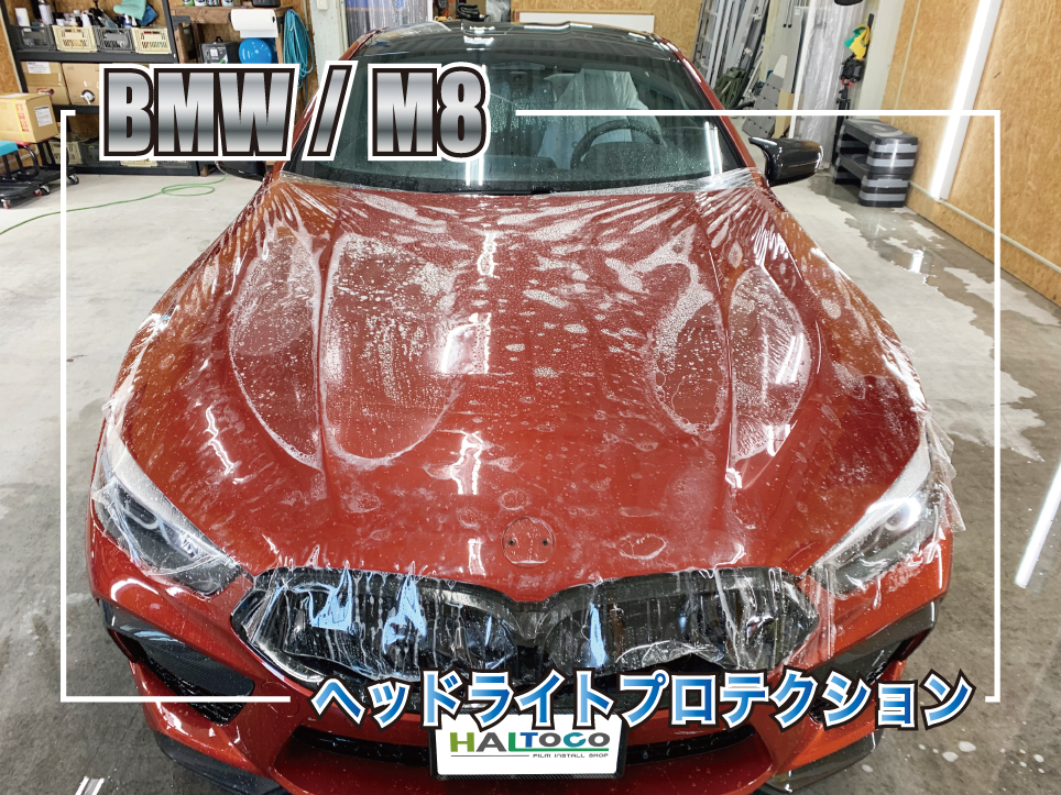 BMW M8のボンネットへプロテクションフィルムを施工している様子。施工液を使用しながら大判フィルムを貼り込み、飛び石や傷対策を行っている作業中の風景。