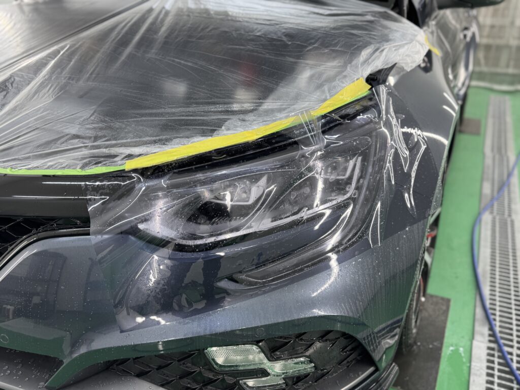 ヘッドライトリペア後の仕上げとして、スモークタイプのプロテクションフィルムを施工している様子