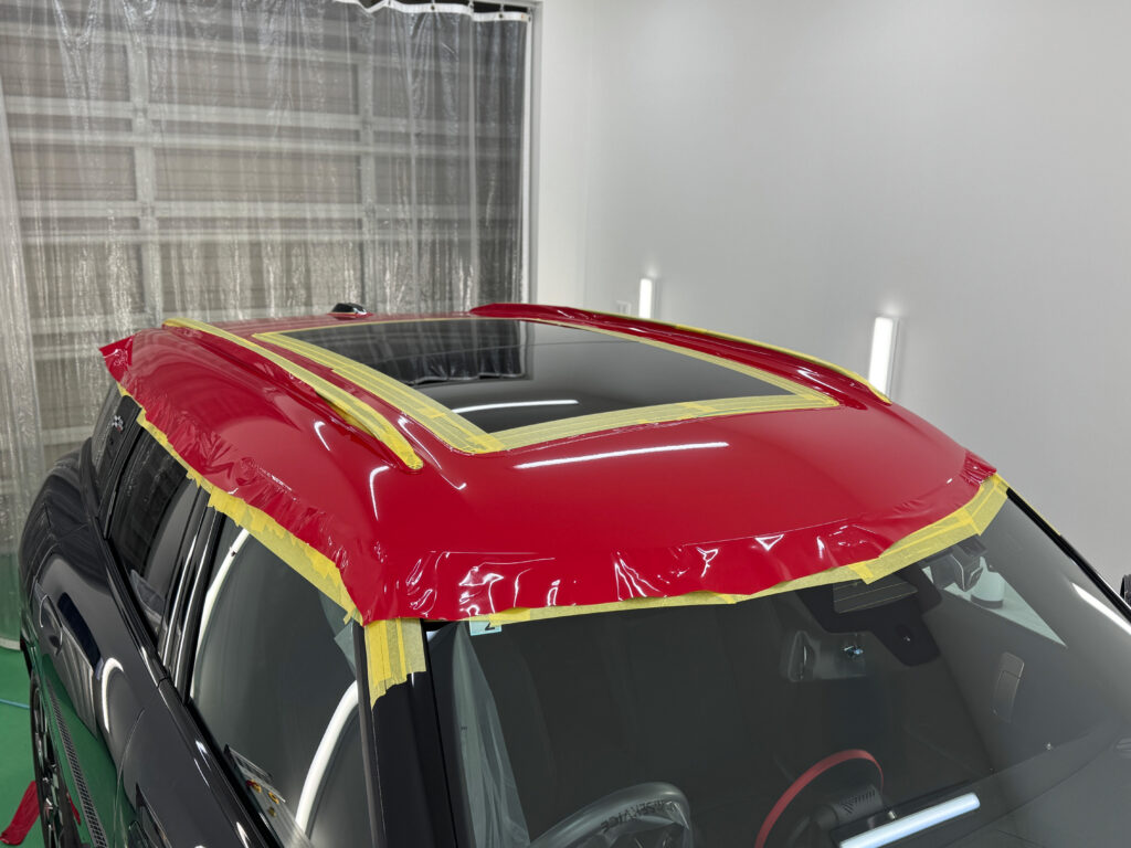 MINI カントリーマン JCWのルーフラッピング施工中の様子。オラカル チリレッドをルーフ全体へ貼り込みしている工程。