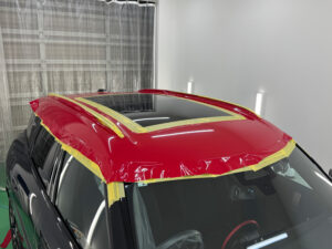 MINI カントリーマン JCWのルーフラッピング施工中の様子。オラカル チリレッドをルーフ全体へ貼り込みしている工程。