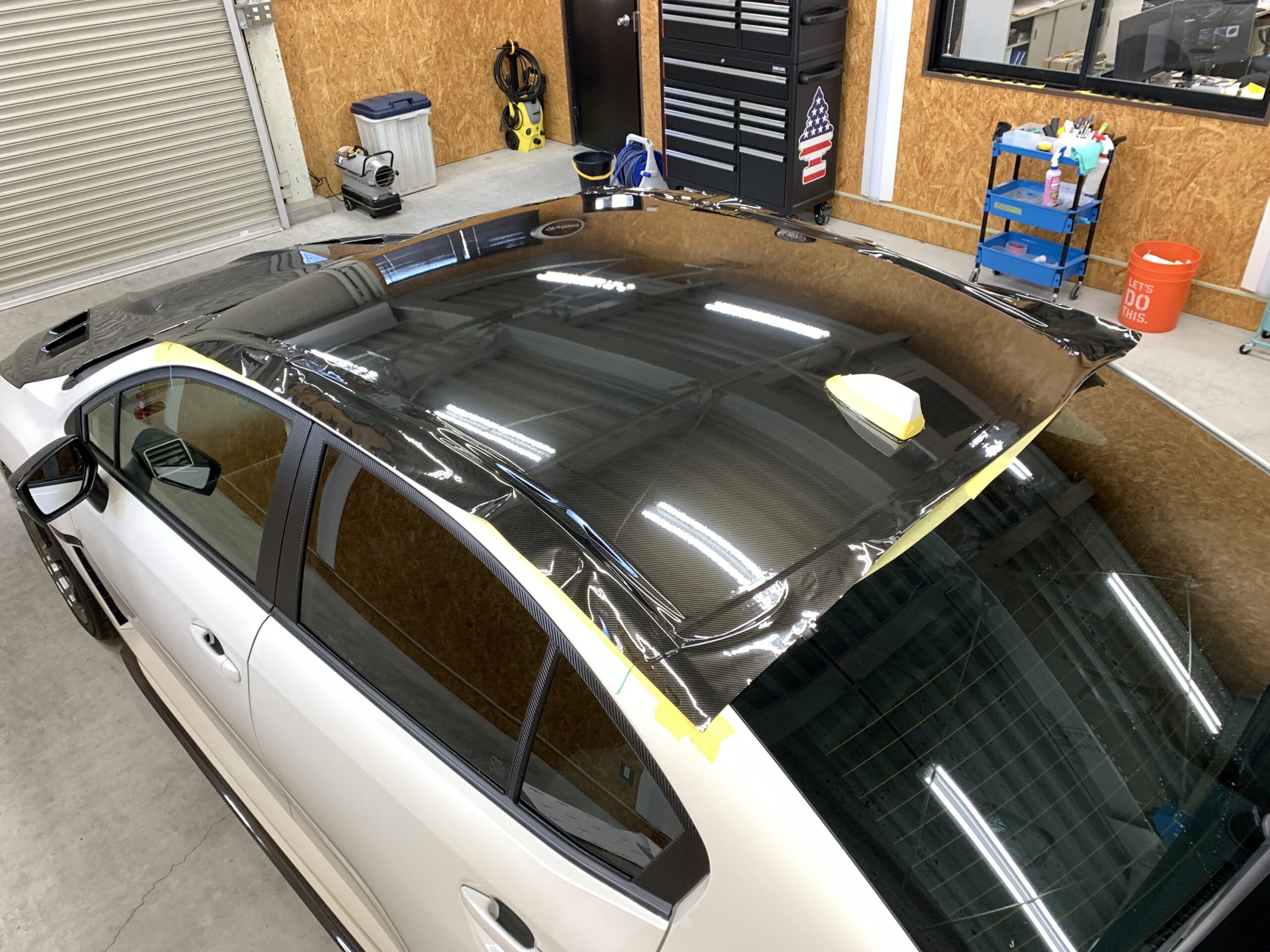 WRXのルーフへグロスカーボン柄フィルムを施工している途中の写真。ルーフ端部やアンテナ周辺までフィルムをしっかり追従させながら施工している様子がわかる。
