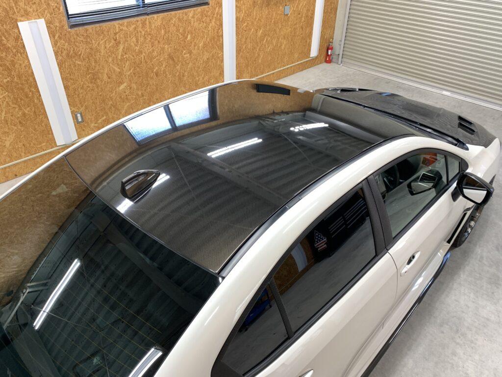 TECKWRAP RCF03を施工したスバルWRXの完成後ルーフ。艶感のあるリアルなカーボン柄がルーフ全面に広がり、ホワイトボディとのコントラストが際立つ仕上がり。