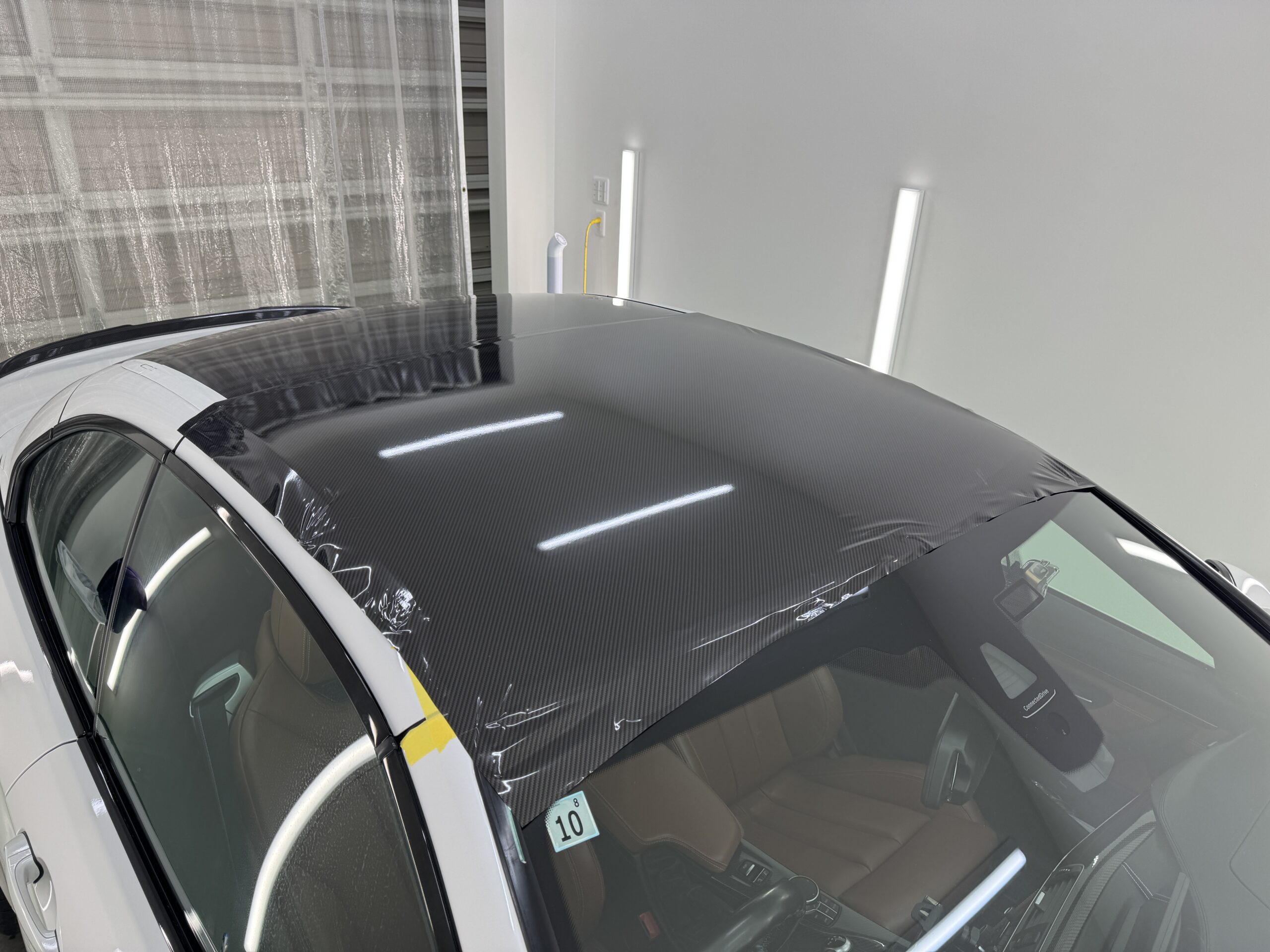 BMW M4カブリオレのルーフへLDカーボンメタリックフィルムを施工している様子