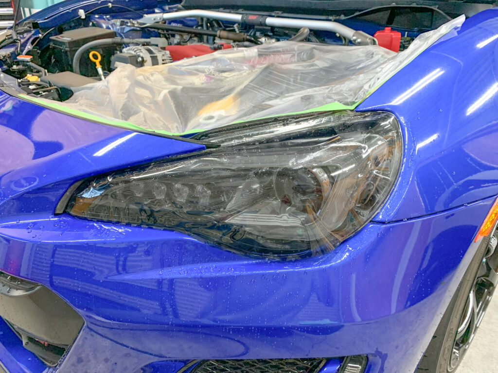 ブラックブラウンのプロテクションフィルムを施工中のBRZヘッドライト