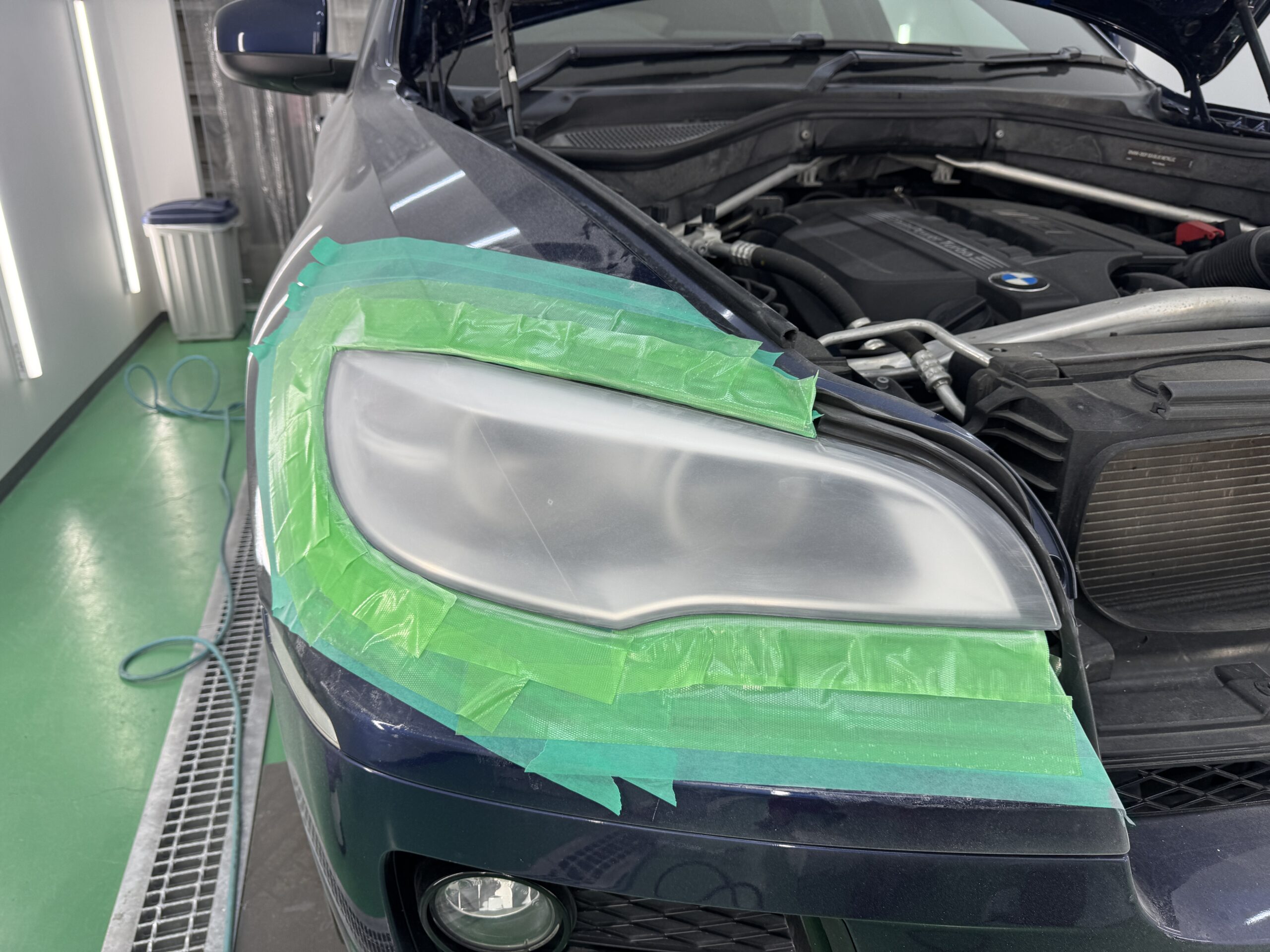 BMW X6のヘッドライト表面に発生したクラックを研磨で除去している作業中