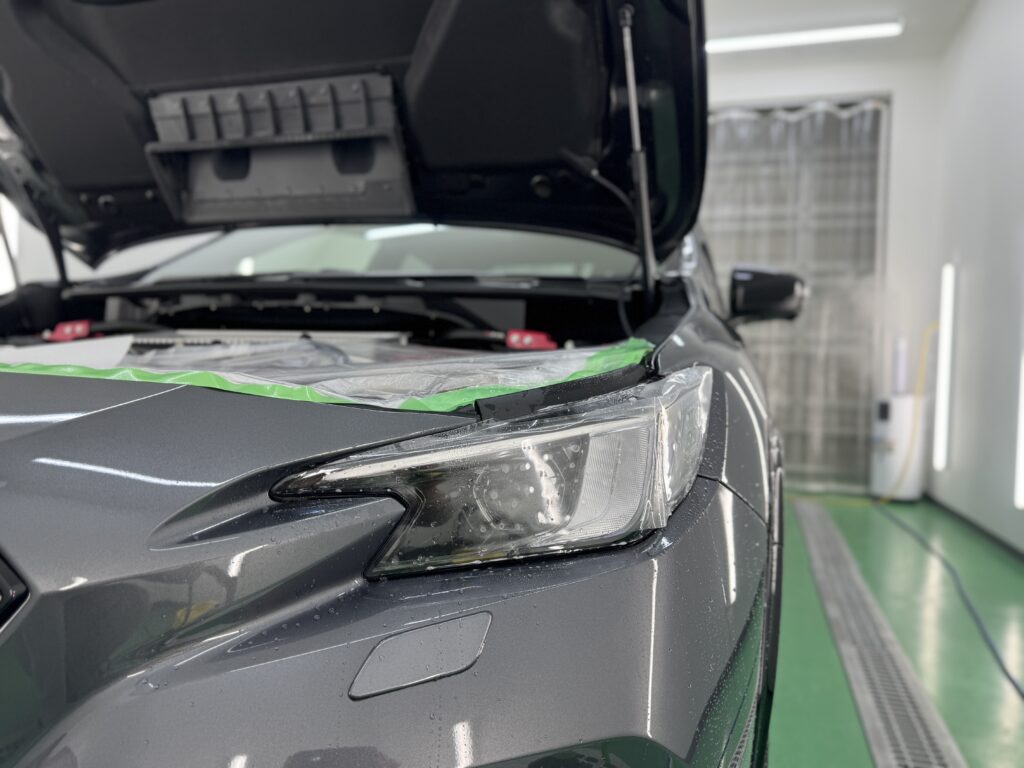 スバル S210のヘッドライトへ透明プロテクションフィルムを施工している様子