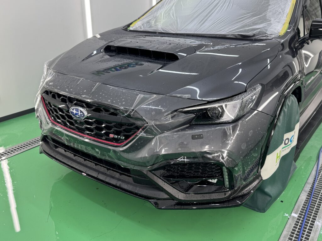 スバル S210のフロントバンパーへプロテクションフィルムを施工している様子