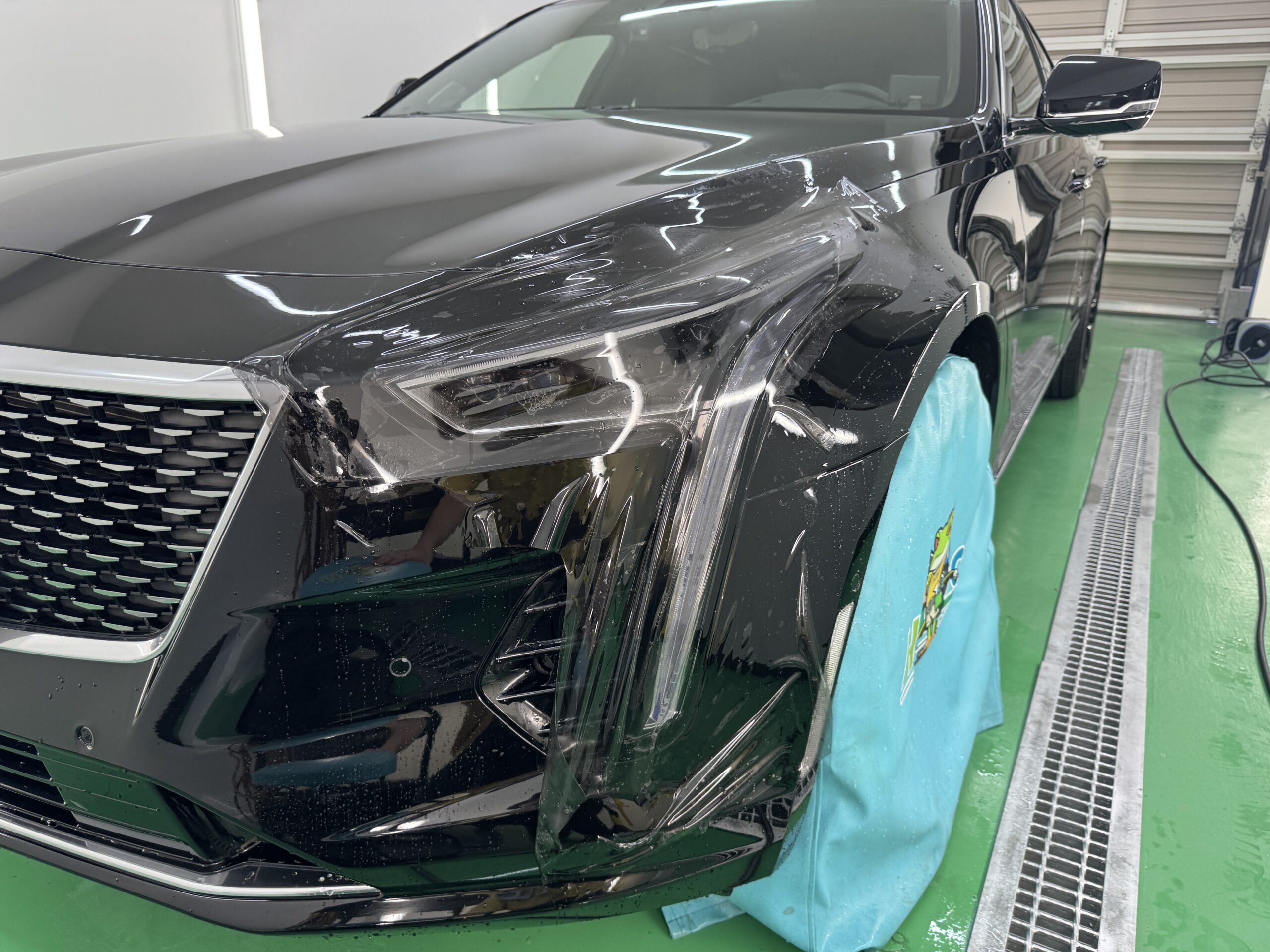 キャデラック CT6のヘッドライトにブラックグレーのスモークPPFを貼り付けている施工中の様子