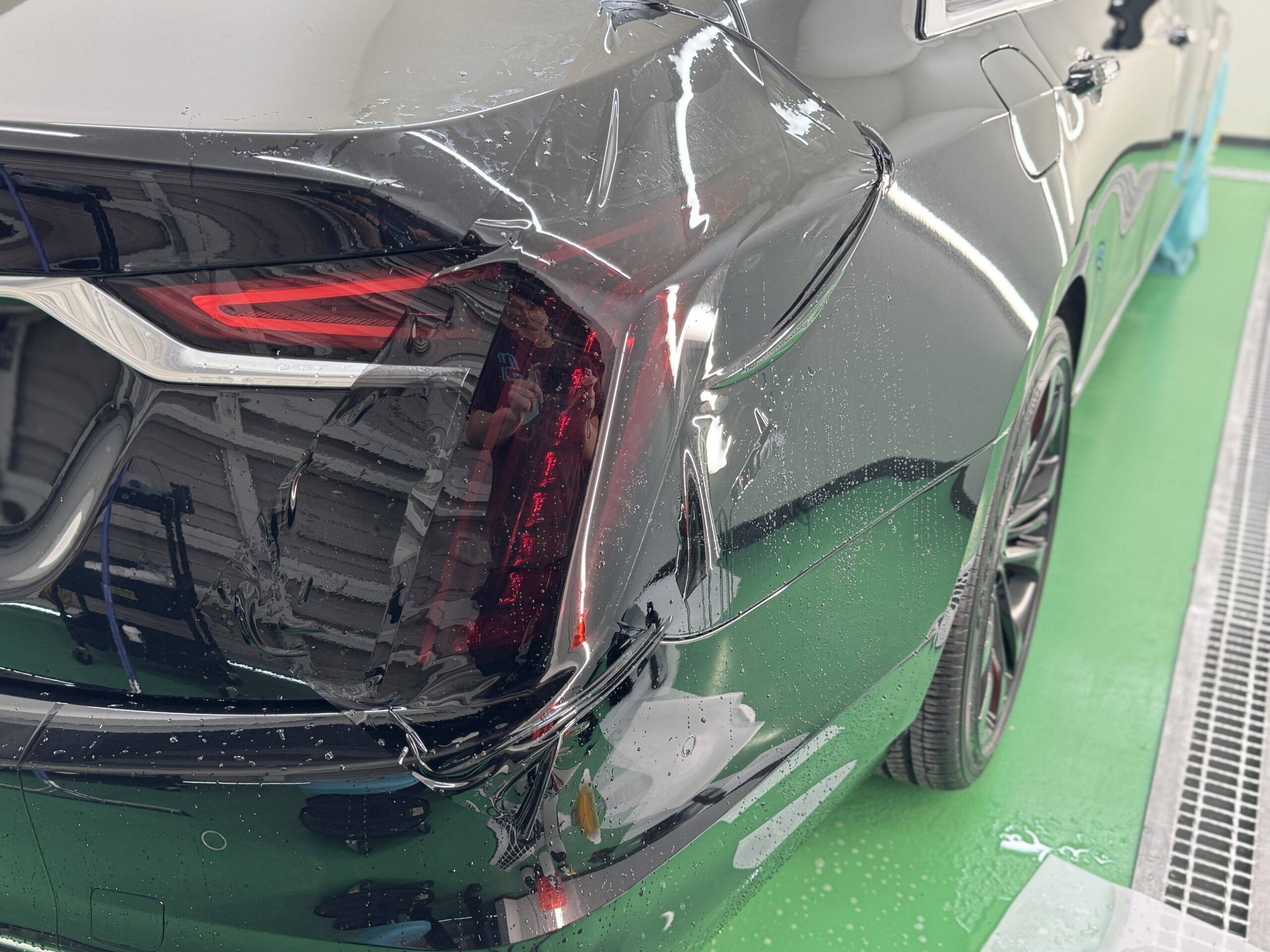 キャデラック CT6のテールランプにスモークPPFを貼り付けている施工中の様子