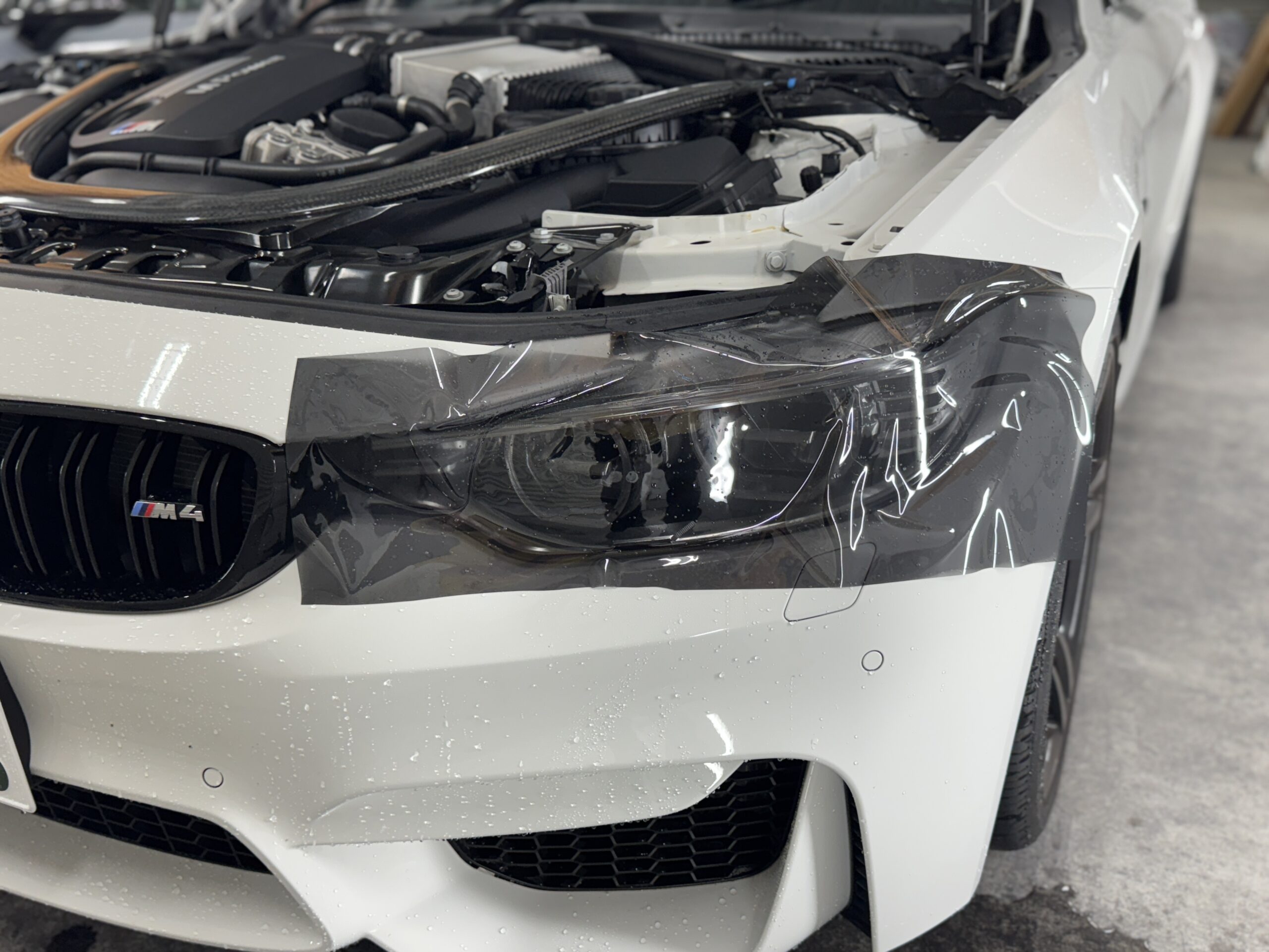 BMW M4のヘッドライトにダイヤモンドスウェル・ブラックブラウンを施工している様子