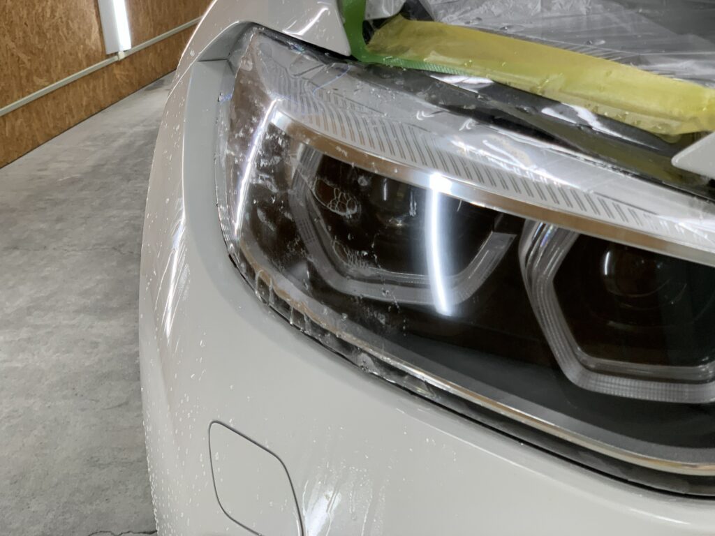 BMW M2 F87 ヘッドライトPPFをスキージーで施工している様子