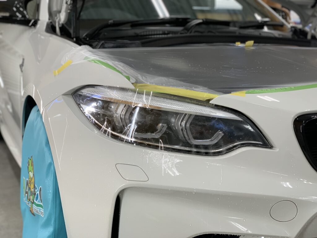 BMW M2 F87 右ヘッドライトに透明PPFを施工している様子