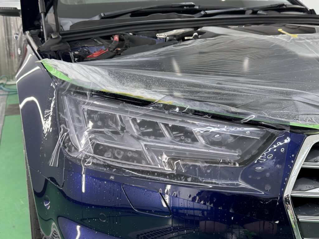 Audi S4 ヘッドライトにブラックヴァイオレットPPFを施工中
