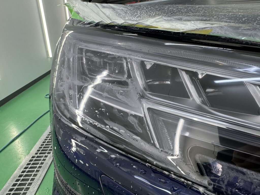 Audi S4 ヘッドライトPPFをスキージングして施工する様子