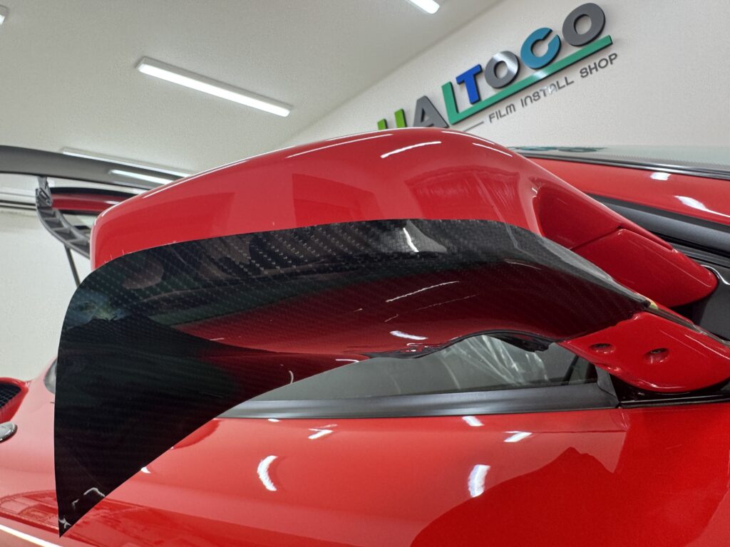 ェラーリF430のドアミラーにグロスカーボンPPFを施工している様子