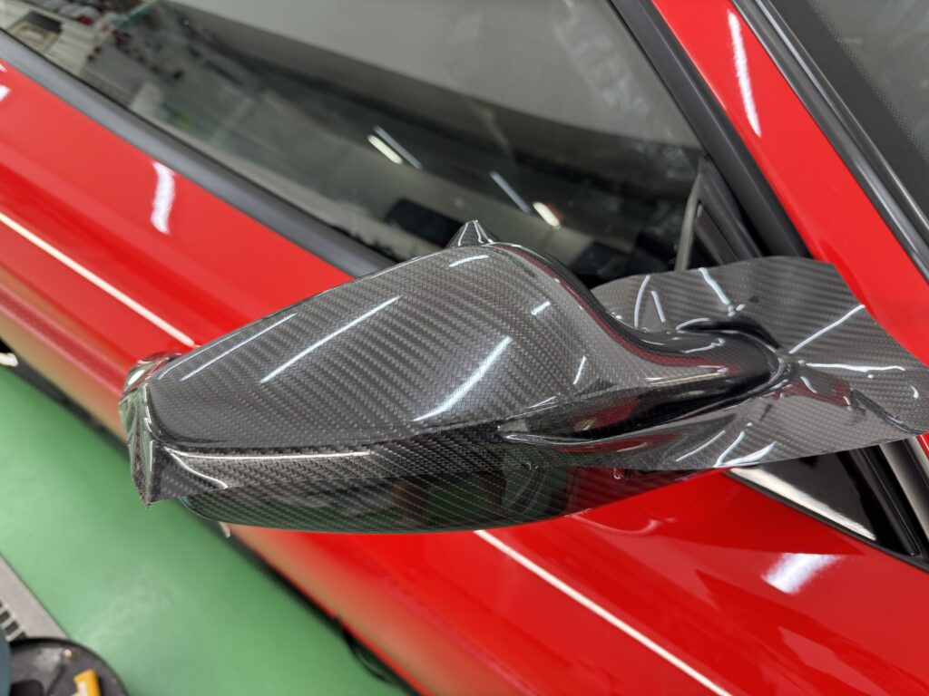 フェラーリF430のドアミラー形状に合わせてグロスカーボンPPFを施工している様子