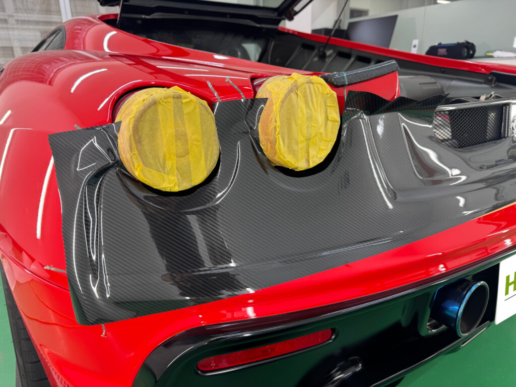 フェラーリF430のリアバンパーにグロスカーボンPPFを施工している様子