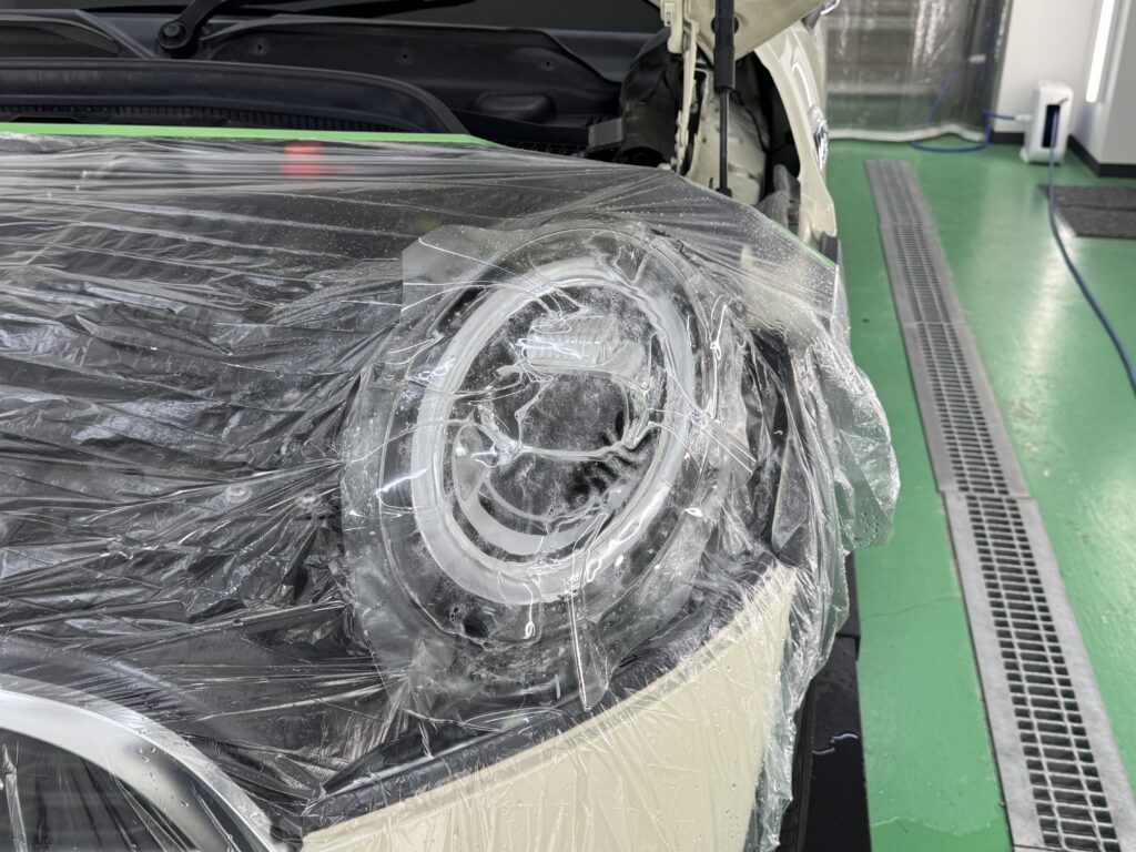 MINI COOPER Sのヘッドライトにプロテクションフィルムを施工している様子