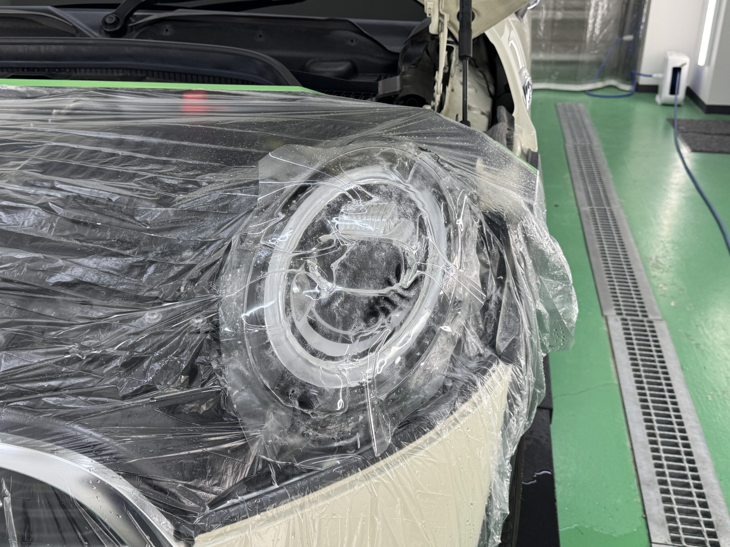MINI COOPER Sのヘッドライトにプロテクションフィルムを施工している様子