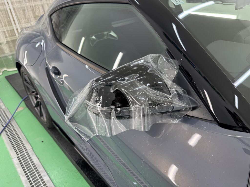 トヨタ GR Supraのドアミラーにプロテクションフィルムを施工している様子
