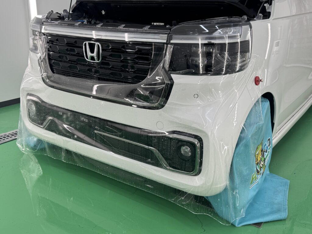 ホンダ N-BOXのフロントバンパーにプロテクションフィルムを施工している様子
