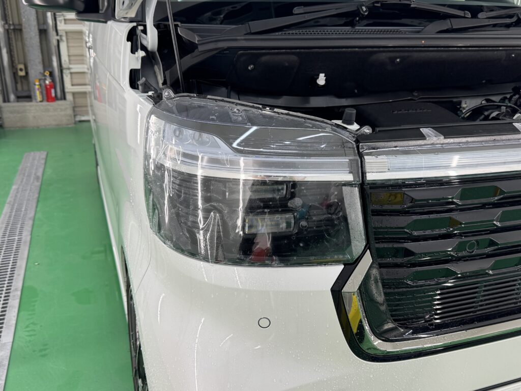 ホンダ N-BOXのヘッドライトにプロテクションフィルムを施工している様子