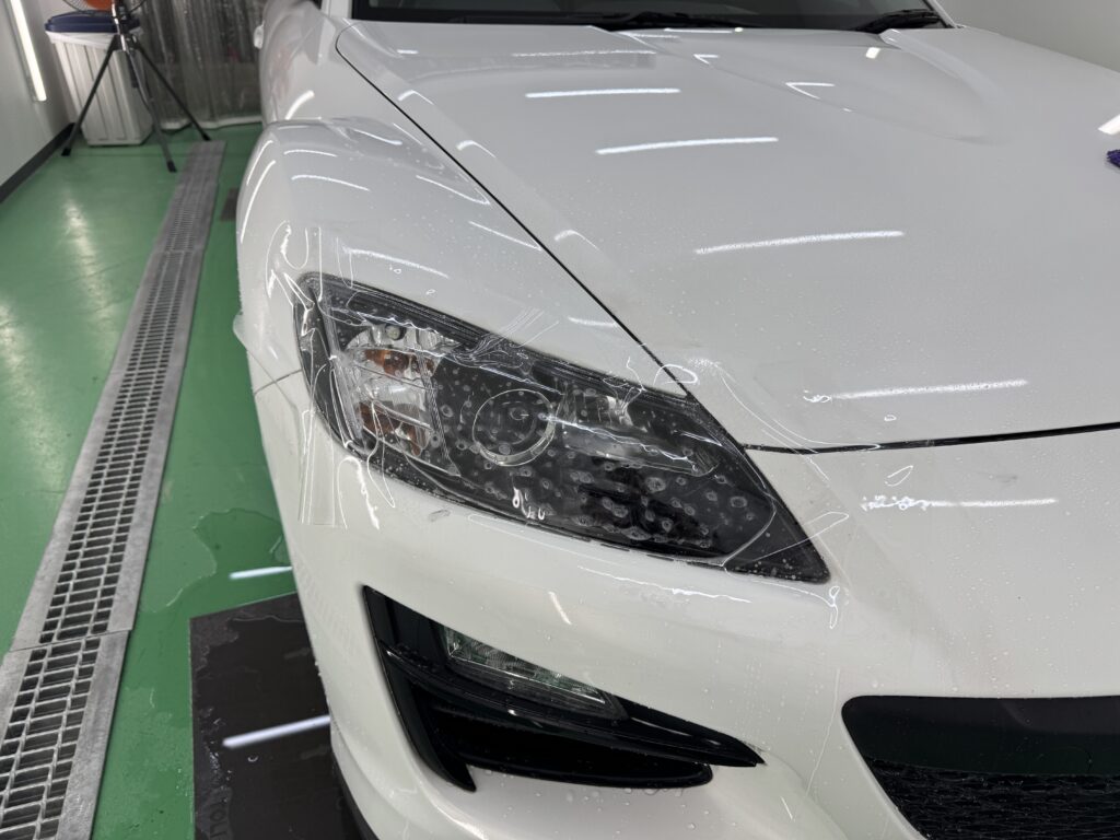 マツダ RX-8のヘッドライトにプロテクションフィルムを施工している様子