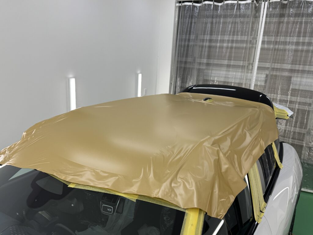 MINI エースマン J05のルーフにマットゴールドのラッピングフィルムを広げた施工中の状態