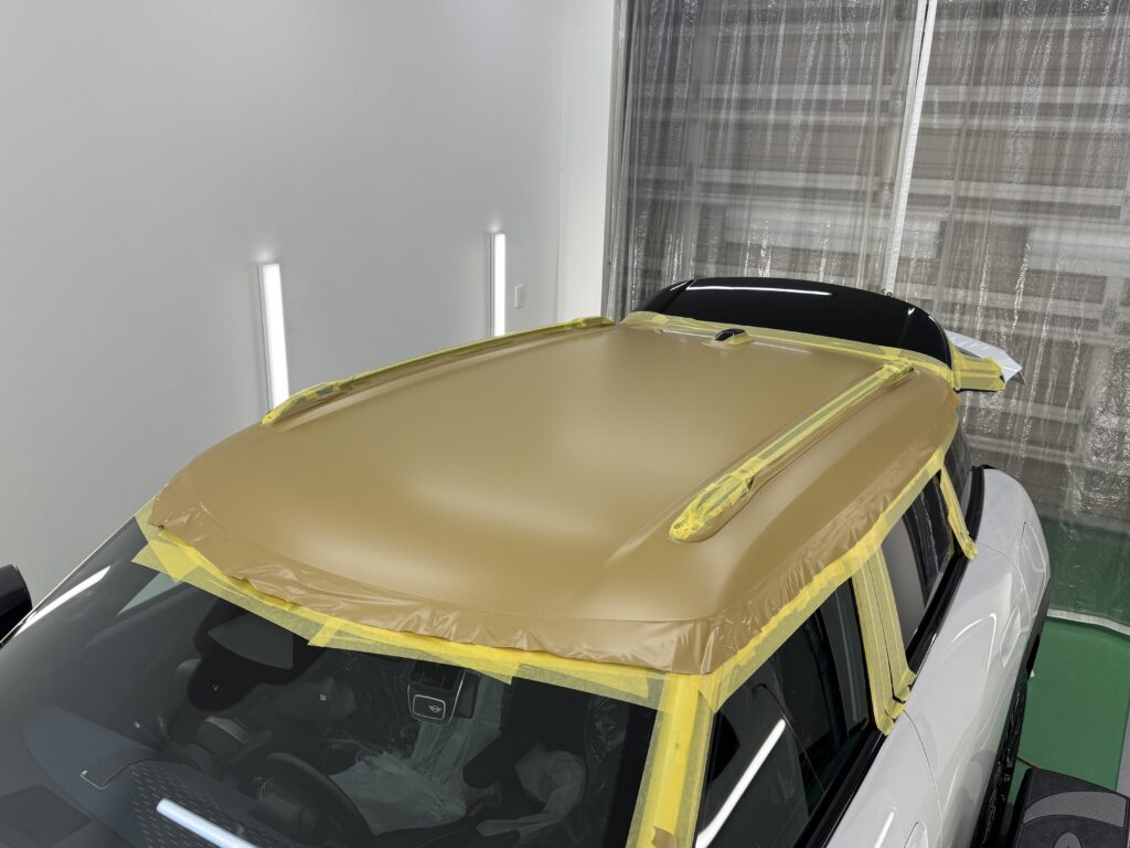 MINI エースマン J05のルーフにマットゴールドのフィルムを施工し、ルーフレール周辺を養生した状態