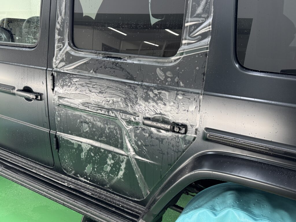 メルセデスAMG G63の左リアドアにマットプロテクションフィルムを施工している様子