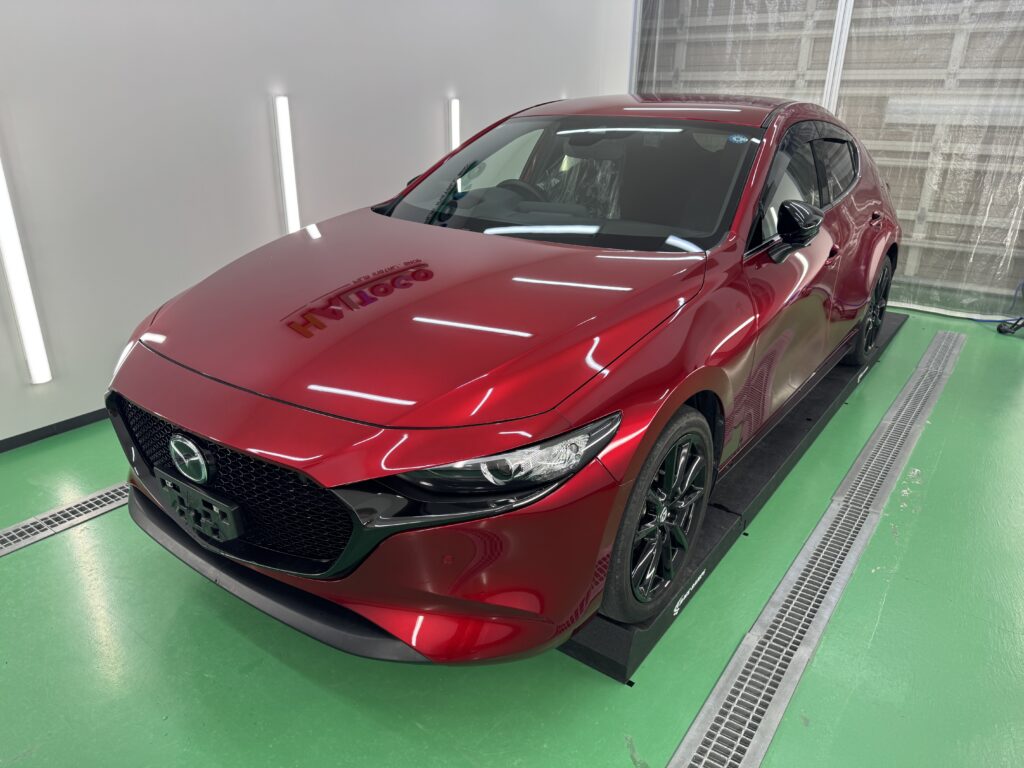 赤いマツダ MAZDA3の入庫時の車両全体を斜め前方から撮影した写真
