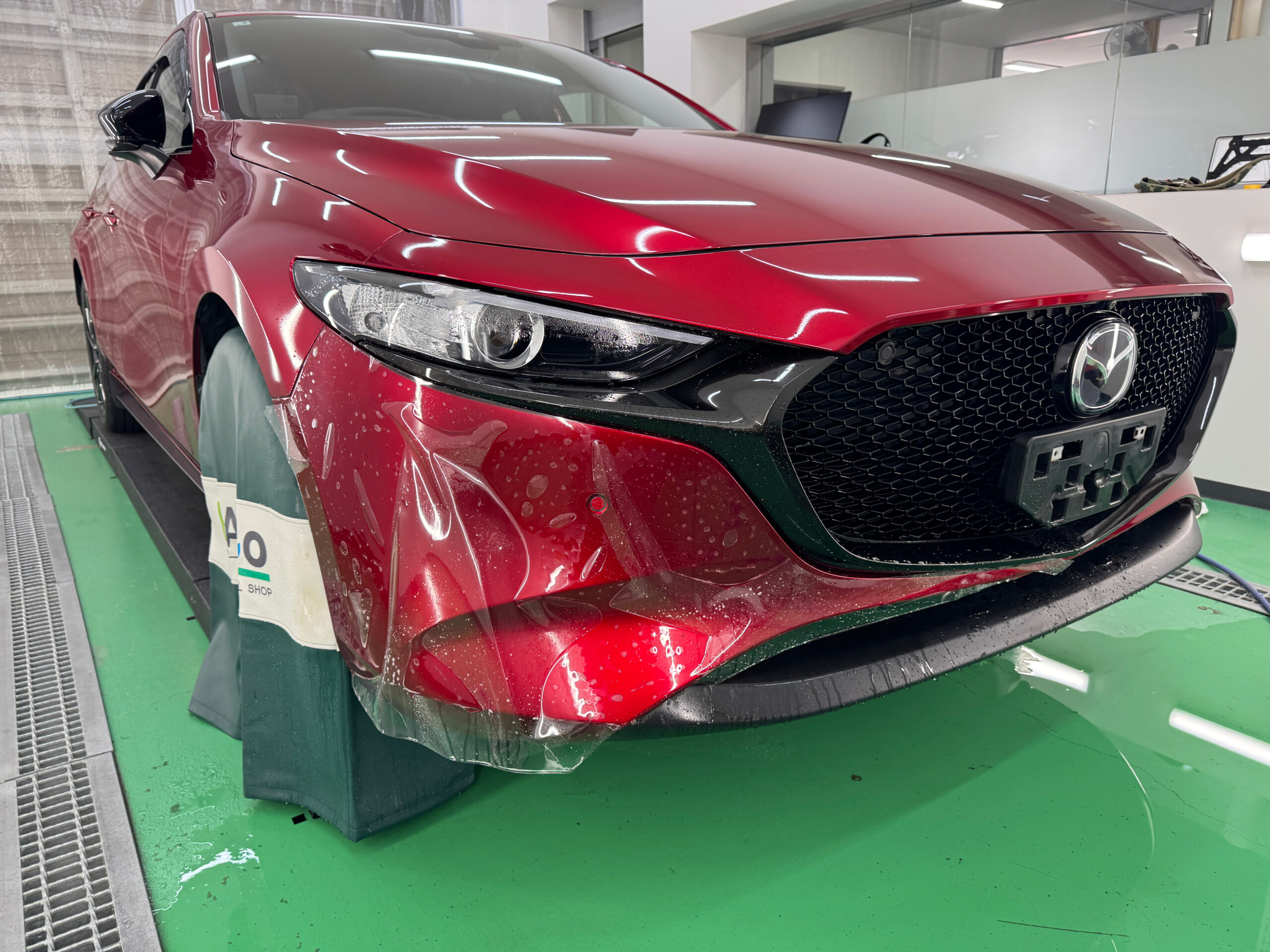 MAZDA3のフロントバンパー下部に透明PPFを貼り付けている途中の様子