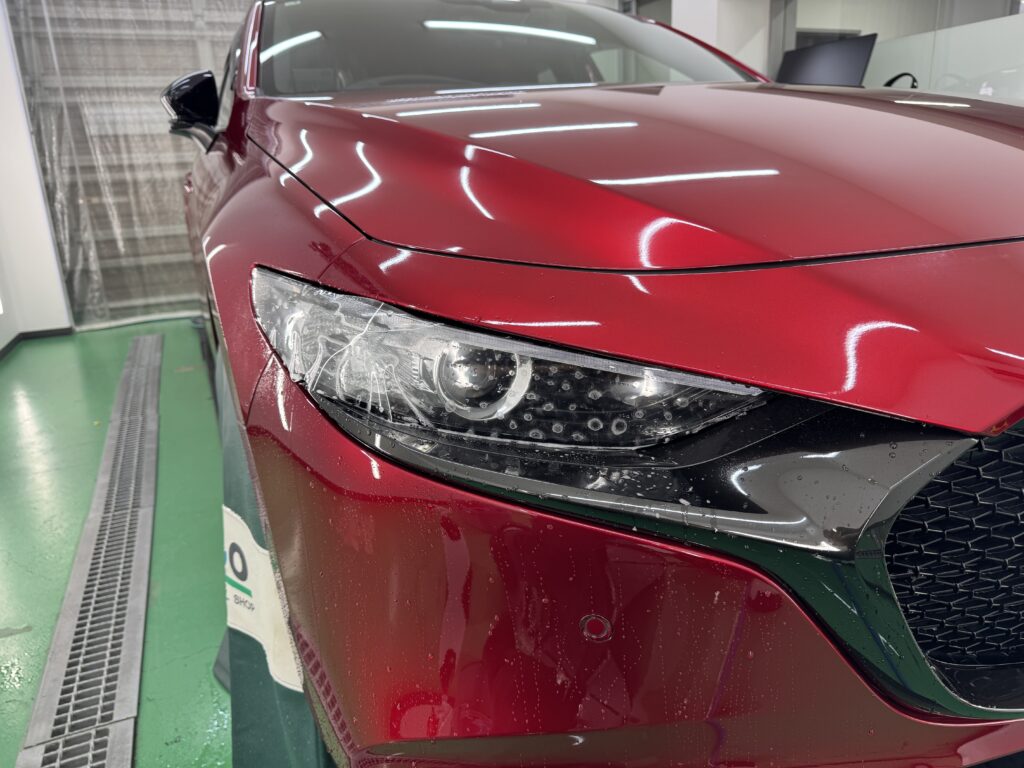 MAZDA3の反対側のヘッドライトに透明PPFを施工している様子