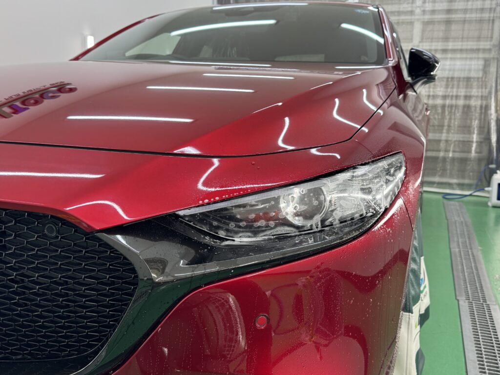 MAZDA3のヘッドライトに透明プロテクションフィルムを施工している様子