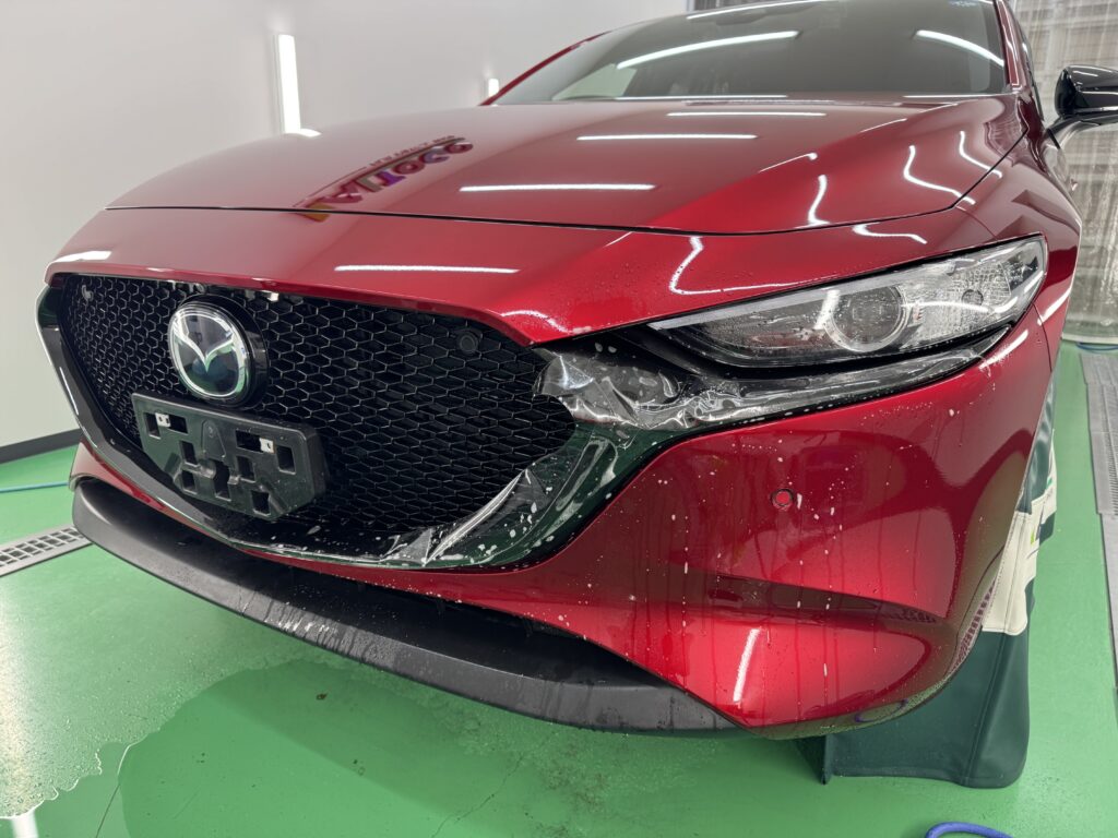 MAZDA3のフロントグリル周囲のグロスブラック部分にPPFを施工している様子